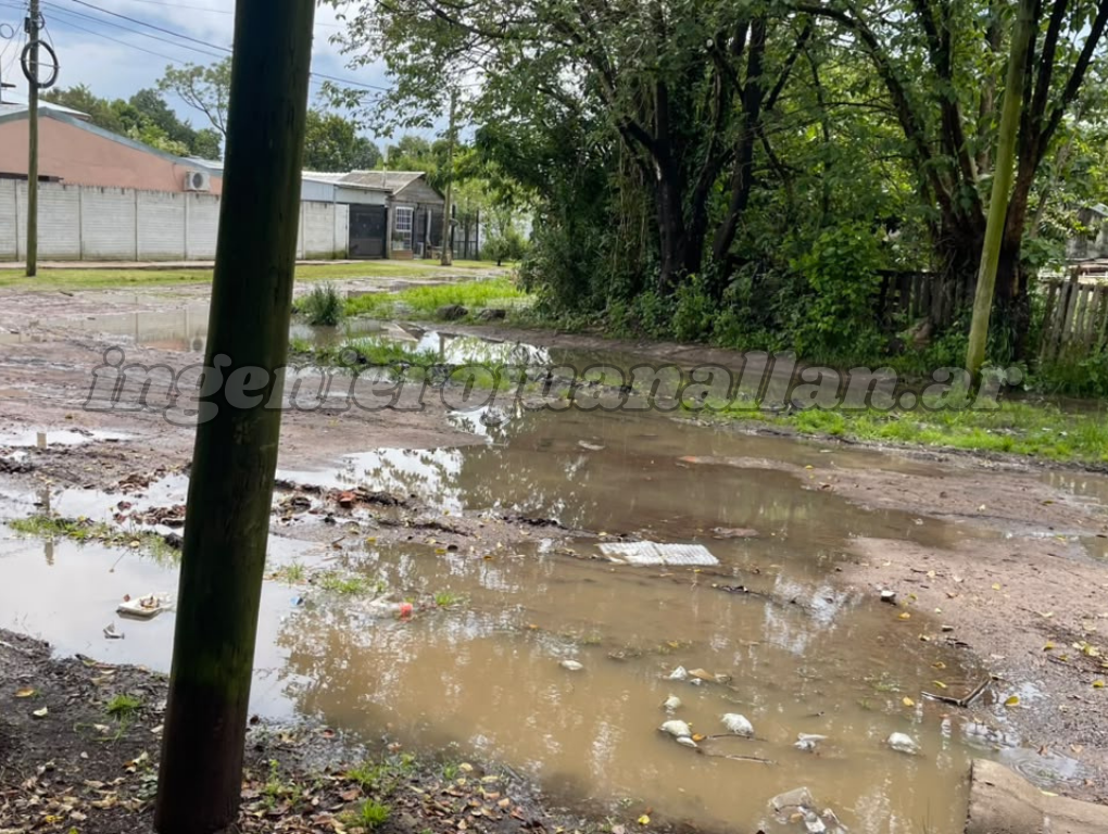 Zanjas tapadas en Cinco Esquinas: calle de tierra de Florencio Varela cubierta de charcos con basura flotando después de la tormenta