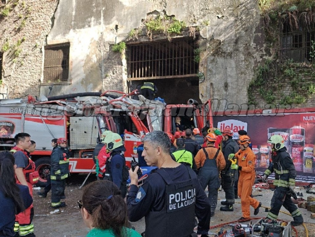 Policía de la Ciudad con un handy frente a la autobomba de Bomberos destruida contra el paredón de la ex cárcel de Caseros