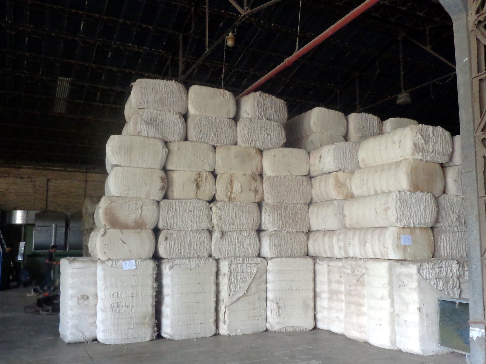 Galpón industrial con fardos blancos apilados bajo un techo de chapa