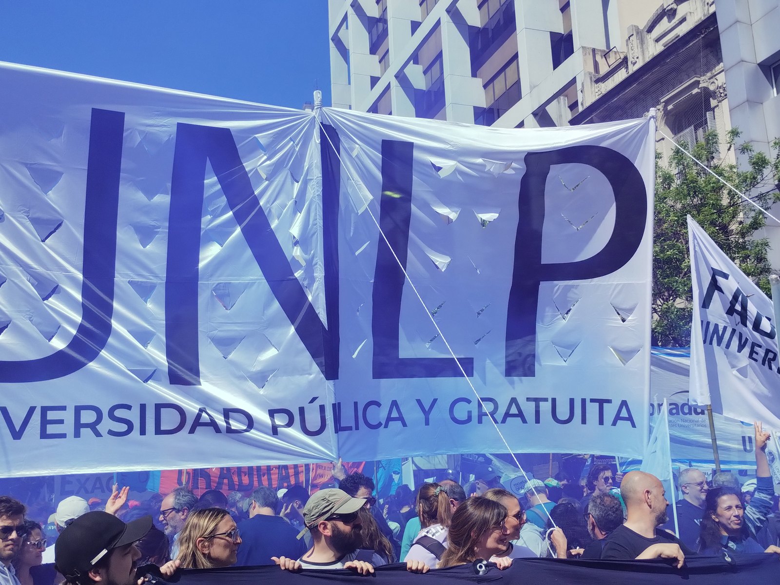 Columna de la Universidad Nacional de La Plata con una gran bandera que dice UNLP, universidad pública y gratuita, durante una marcha universitaria