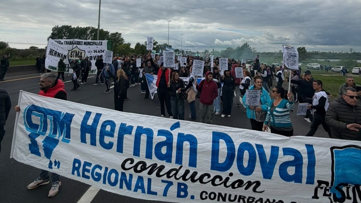 Trabajadores municipales con una bandera de FESIMUBO durante el corte en la autopista Buenos Aires-La Plata