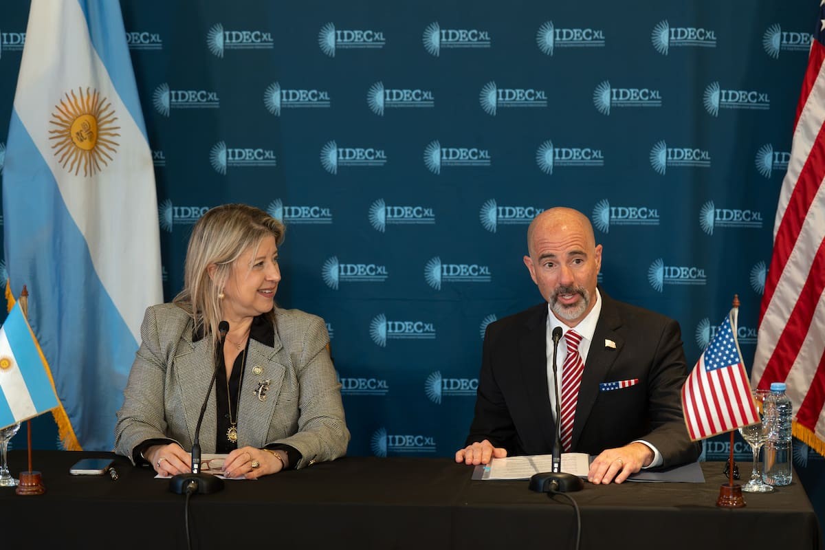 La ministra de Seguridad Nacional, Alejandra Monteoliva, sentada junto a un funcionario estadounidense en una conferencia, con banderas de la Argentina y de Estados Unidos