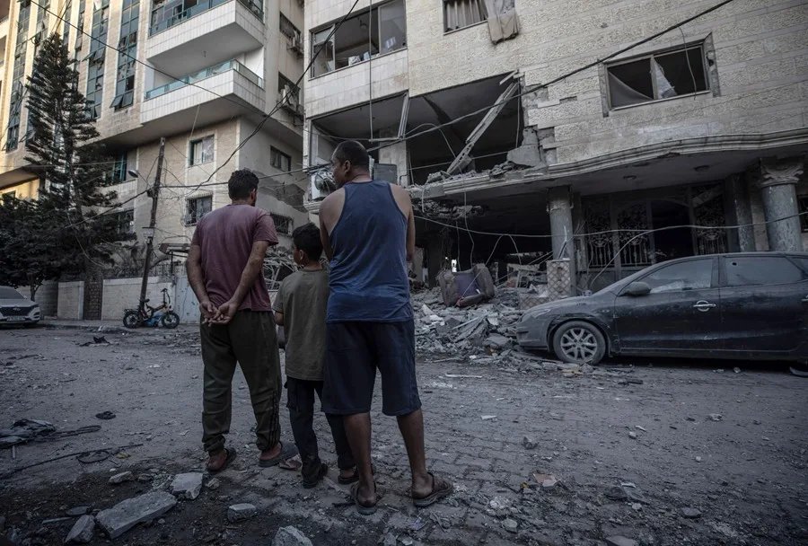 Palestinos observan un edificio dañado tras un ataque aéreo en Ciudad de Gaza