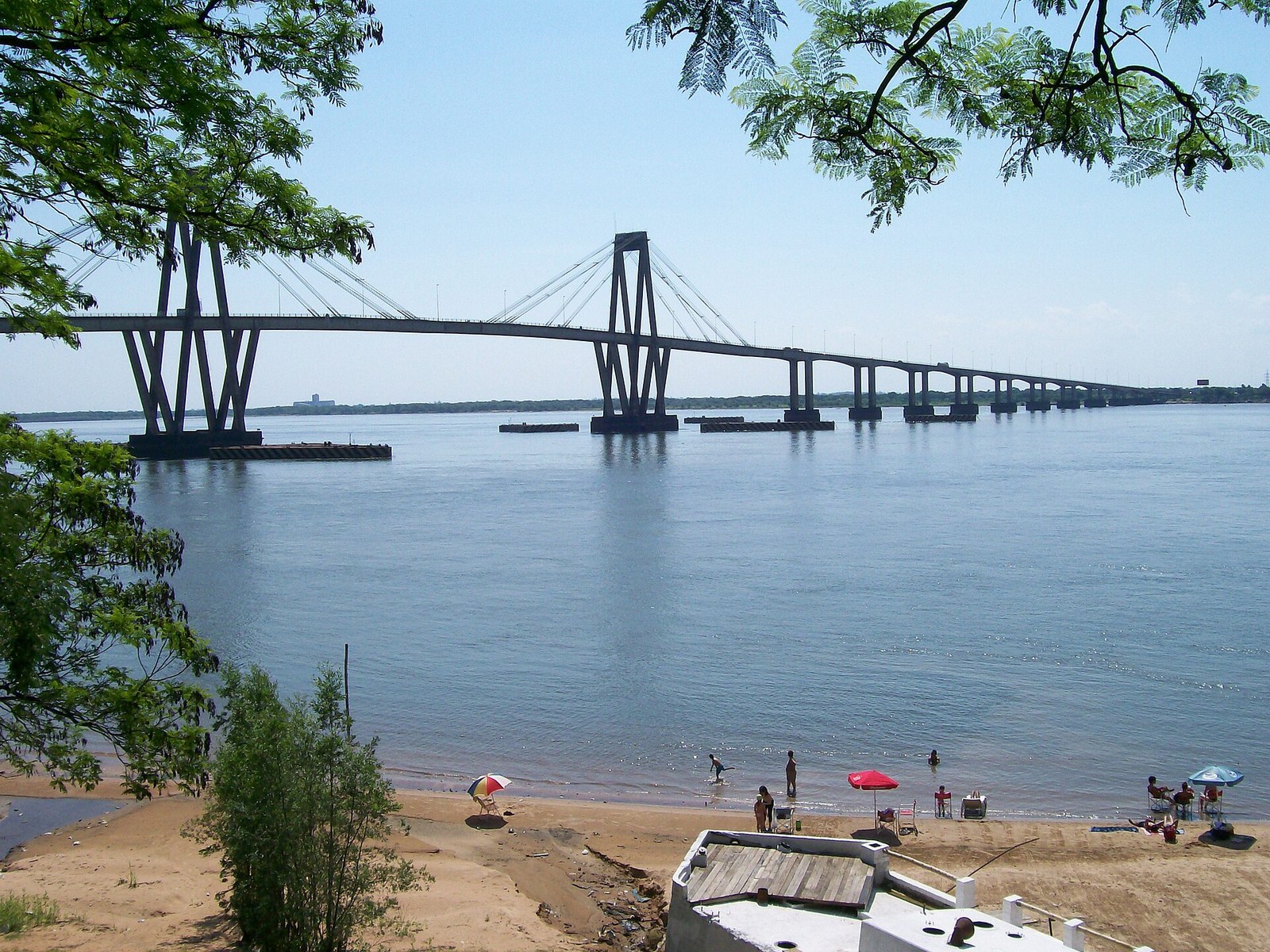 Río Paraná frente a la ciudad de Corrientes, con una playa en primer plano y el puente General Belgrano al fondo