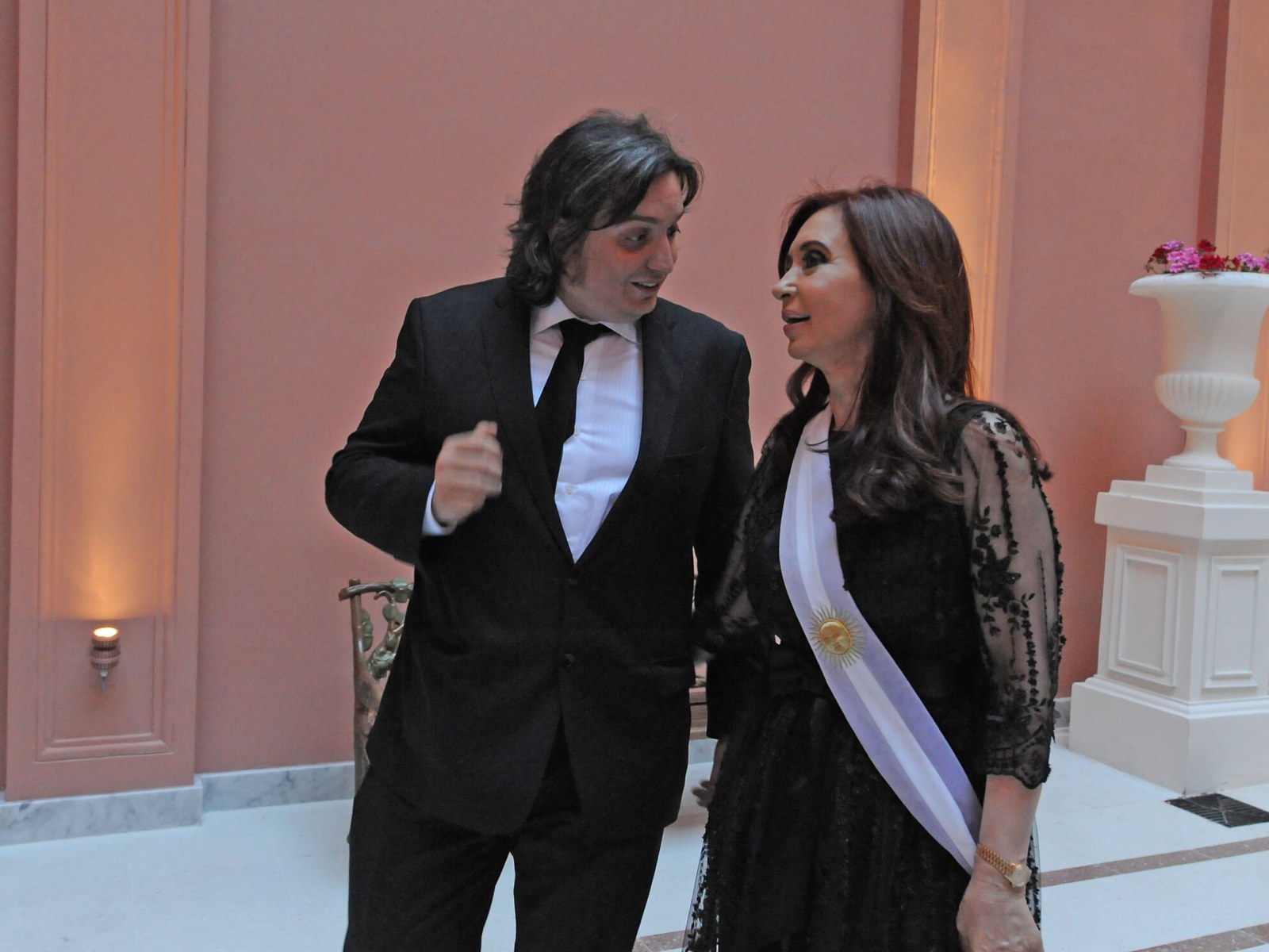 Cristina Fernández de Kirchner, con la banda presidencial, conversa con su hijo Máximo Kirchner en un salón de la Casa Rosada