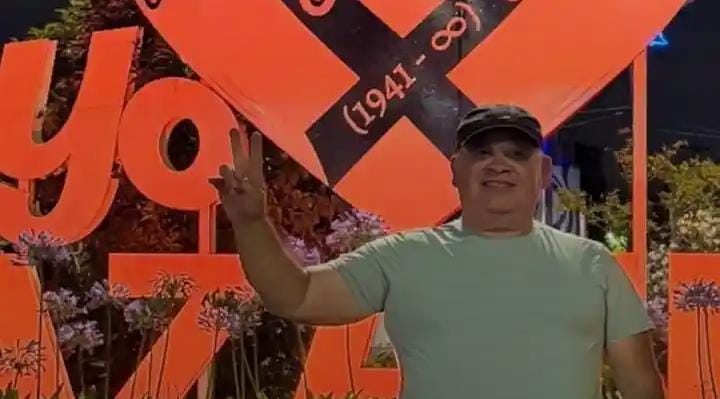 Roberto Chorne hace la V frente a un cartel naranja en Berazategui